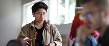 Asian woman talking with another women with a man blurred out in the forground